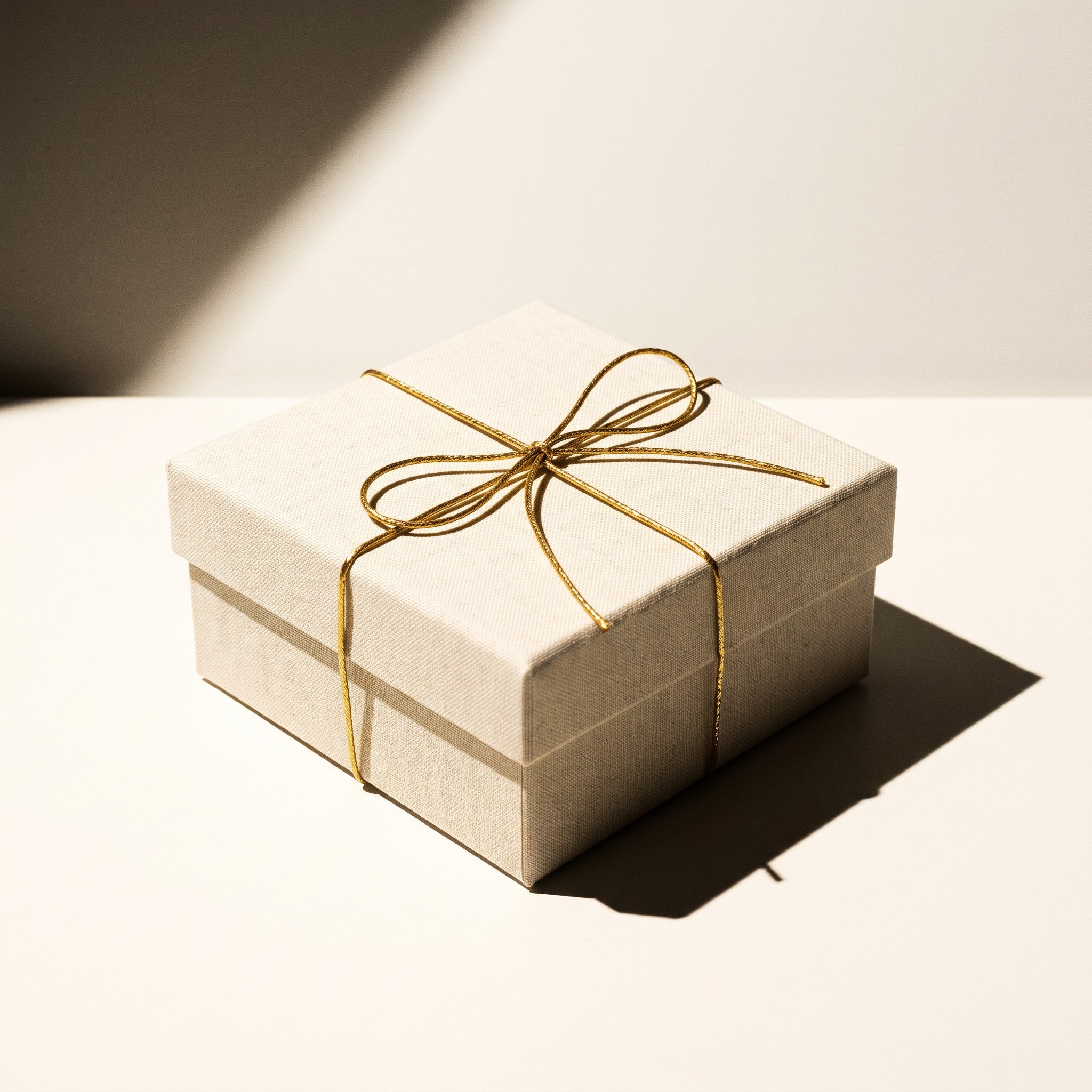 Wrapped gift with gold twine on cream linen